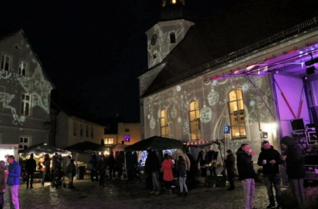 Beleuchtete Kirche und Menschen-Trubel in Drebkau