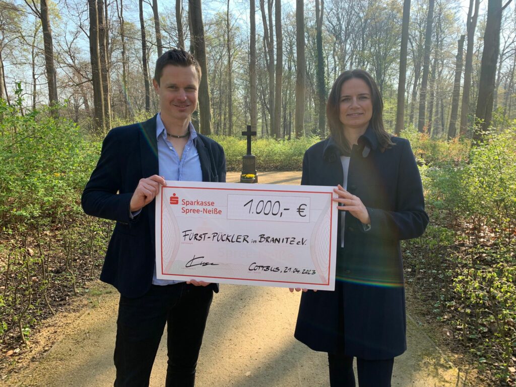 Stephan Klausch, stellvertretender Vorsitzender des Fürst-Pückler-Vereins, und Anne Klose, Leiterin der Sparkassen-Geschäftsstelle am Breitscheidplatz, zeigen den Scheck der Sparkasse für den neuen „verlorenen Ort“.