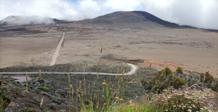 Der Weg durch die weite, öde Kaldera führt hinüber in die Nähe des aktiven Vulkans Pilon de la Fournaise, der seinen Gipfel in den Wolken versteckt. Vier Tage zuvor ist er zuletzt ausgebrochen. 