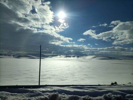 Am Pass auf 2.410 Meter Höhe verschmelzen Schneeweiten und Wolken unter blauem Himmel noch zu romantischer Stille